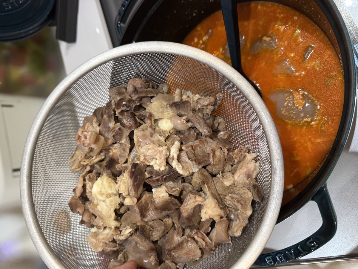 Adding tender, slow-simmered beef tendon pieces into the aromatic base