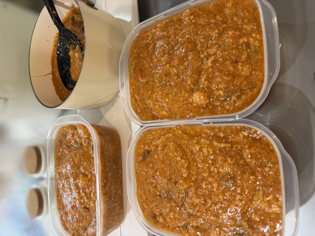 Portioning the cooked mapo base into clean Tupperware containers for bulk freezer storage
