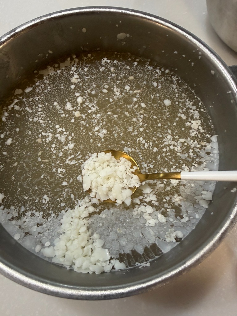 冷蔵庫で冷やして白く固まった牛すじスープの余分な脂をスプーンで取り除く様子